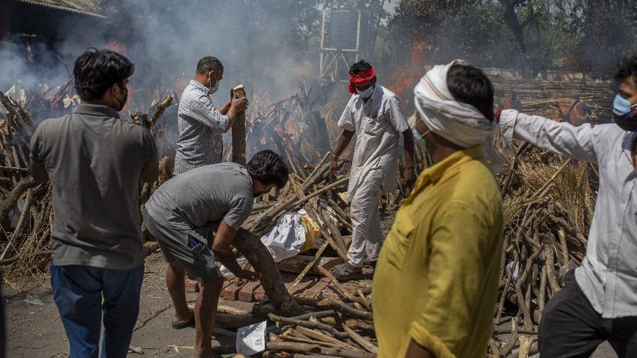 Members of a family of COVID-19 victim prepare funeral pyre for deceased member as multiple funeral pyres of those who died of COVID-19 are seen at a crematorium in New Delhi, India, Saturday, April 24, 2021. Delhi has been cremating so many bodies of coronavirus victims that authorities are getting requests to start cutting down trees in city parks, as a second record surge has brought India's tattered healthcare system to its knees. (AP Photo/Altaf Qadri)