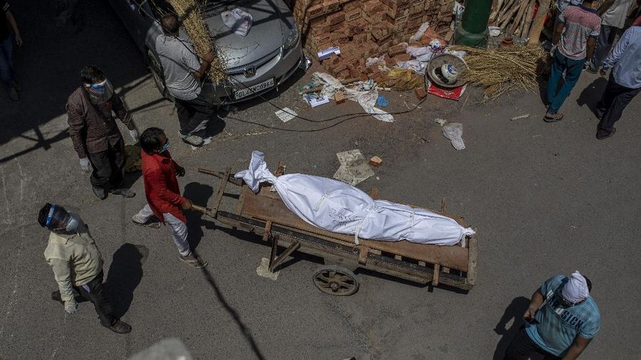 A man transports a dead body on a handcart to a ground that has been converted into a crematorium for mass cremation of COVID-19 victims, in New Delhi, India, Saturday, April 24, 2021. Delhi has been cremating so many bodies of coronavirus victims that authorities are getting requests to start cutting down trees in city parks, as a second record surge has brought India's tattered healthcare system to its knees. (AP Photo/Altaf Qadri)
