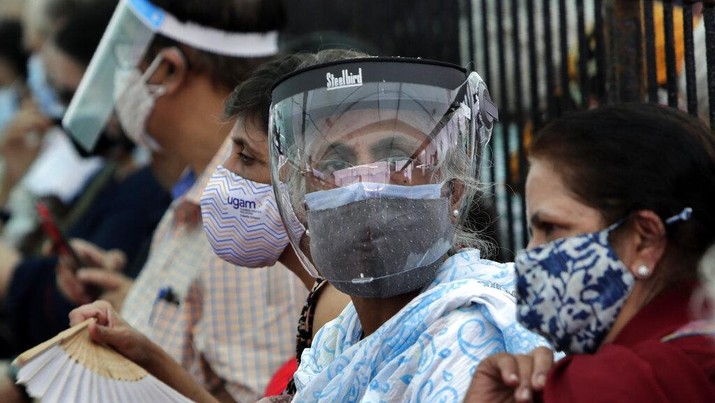 People wearing face shields and masks as a precaution against the coronavirus as they wait to receive COVID-19 vaccine in Mumbai, India, Thursday, April 29, 2021. India set another global record in new virus cases Thursday, as millions of people in one state cast votes despite rising infections and the country geared up to open its vaccination rollout to all adults amid snags. (AP Photo/Rajanish Kakade)