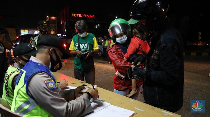 Petugas kepolisian memeriksa dokumen pengendara yang melintas dari arah Jakarta menuju Merak di pintu Gerbang Tol Merak, Banten, Kamis (6/5/2021) dini hari. Pemeriksaan tersebut terkait larangan mudik lebaran 2021 yang dimulai dari tanggal 6 hingga 17 Mei sebagai upaya mengantisipasi risiko peningkatan kasus penularan COVID-19 jelang perayaan Hari Raya Idul Fitri 1442 H. (CNBC Indonesia/Andrean Kristianto)