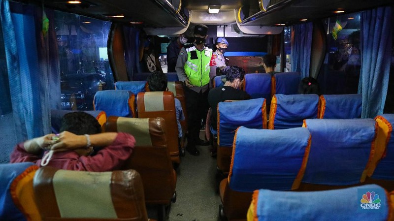 Petugas kepolisian memeriksa dokumen pengendara yang melintas dari arah Jakarta menuju Merak di pintu Gerbang Tol Merak, Banten, Kamis (6/5/2021) dini hari. Pemeriksaan tersebut terkait larangan mudik lebaran 2021 yang dimulai dari tanggal 6 hingga 17 Mei sebagai upaya mengantisipasi risiko peningkatan kasus penularan COVID-19 jelang perayaan Hari Raya Idul Fitri 1442 H. (CNBC Indonesia/Andrean Kristianto)