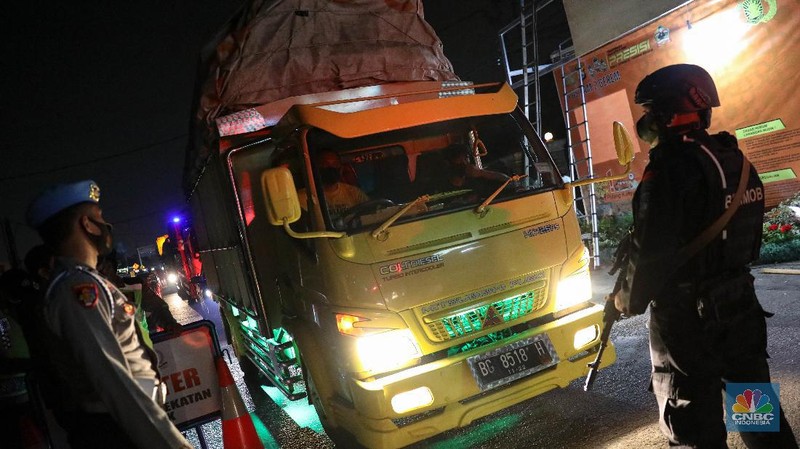 Petugas kepolisian memeriksa dokumen pengendara yang melintas dari arah Jakarta menuju Merak di pintu Gerbang Tol Merak, Banten, Kamis (6/5/2021) dini hari. Pemeriksaan tersebut terkait larangan mudik lebaran 2021 yang dimulai dari tanggal 6 hingga 17 Mei sebagai upaya mengantisipasi risiko peningkatan kasus penularan COVID-19 jelang perayaan Hari Raya Idul Fitri 1442 H. (CNBC Indonesia/Andrean Kristianto)