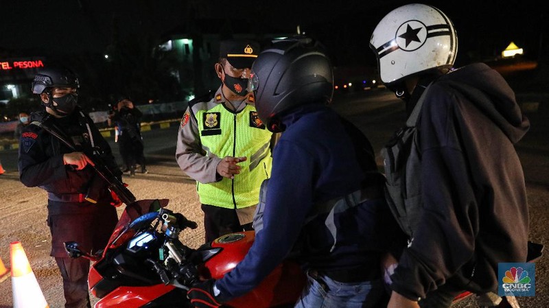 Petugas kepolisian memeriksa dokumen pengendara yang melintas dari arah Jakarta menuju Merak di pintu Gerbang Tol Merak, Banten, Kamis (6/5/2021) dini hari. Pemeriksaan tersebut terkait larangan mudik lebaran 2021 yang dimulai dari tanggal 6 hingga 17 Mei sebagai upaya mengantisipasi risiko peningkatan kasus penularan COVID-19 jelang perayaan Hari Raya Idul Fitri 1442 H. (CNBC Indonesia/Andrean Kristianto)