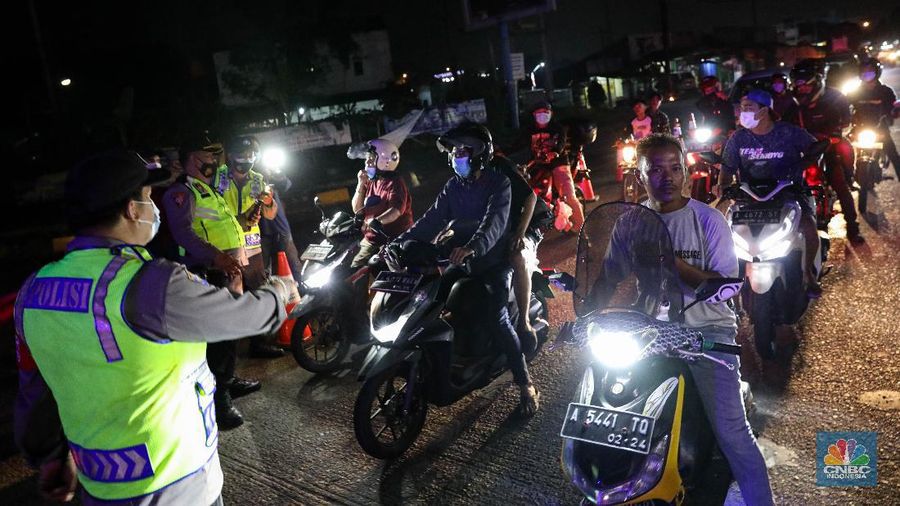 Petugas kepolisian memeriksa dokumen pengendara yang melintas di Pospam Gerem, Cilegon, Banten, Kamis (6/5/2021) dini hari. Pemeriksaan tersebut terkait larangan mudik lebaran 2021 yang dimulai dari tanggal 6 hingga 17 Mei sebagai upaya mengantisipasi risiko peningkatan kasus penularan COVID-19 jelang perayaan Hari Raya Idul Fitri 1442 H. (CNBC Indonesia/Andrean Kristianto)