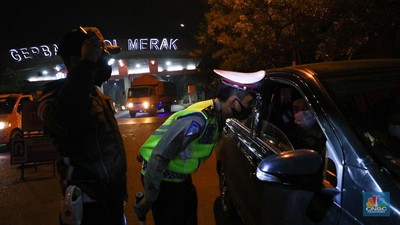 Penyekatan Pemudik di Tol Merak Petugas kepolisian memeriksa dokumen pengendara yang melintas dari arah Jakarta menuju Merak di pintu Gerbang Tol Merak, Banten, Kamis (6/5/2021) dini hari. Pemeriksaan tersebut terkait larangan mudik lebaran 2021 yang dimulai dari tanggal 6 hingga 17 Mei sebagai upaya mengantisipasi risiko peningkatan kasus penularan COVID-19 jelang perayaan Hari Raya Idul Fitri 1442 H. (CNBC Indonesia/Andrean Kristianto)