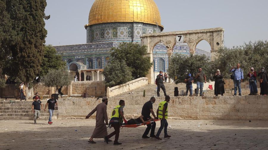 Palestinians evacuate a wounded man during clashes with Israeli security forces in front of the Dome of the Rock Mosque at the Al Aqsa Mosque compound in Jerusalem's Old City Monday, May 10, 2021. Israeli police clashed with Palestinian protesters at a flashpoint Jerusalem holy site on Monday, the latest in a series of confrontations that is pushing the contested city to the brink of eruption. Palestinian medics said at least 180 Palestinians were hurt in the violence at the Al-Aqsa Mosque compound, including 80 who were hospitalized. (AP Photo/Mahmoud Illean)