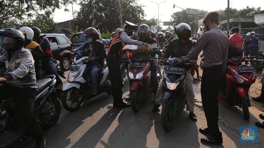 Petugas memeriksa dokumen pengendara motor di pos penyekatan, Jalur Pantura Kedungwaringin, perbatasan Kabupaten Bekasi-Karawang, Senin (10/5/2021).  Dari data yang didpat dari  jam 8.00 wib hingga 12.00 wib sebayak 415 kendaraan yang terdiri dari 342 kendaraan roda dua, 69 kendaraan roda empat, 2 travel dan 2 pickup telah di putar balik. (CNBC Indonesia/Andrean Kristianto)