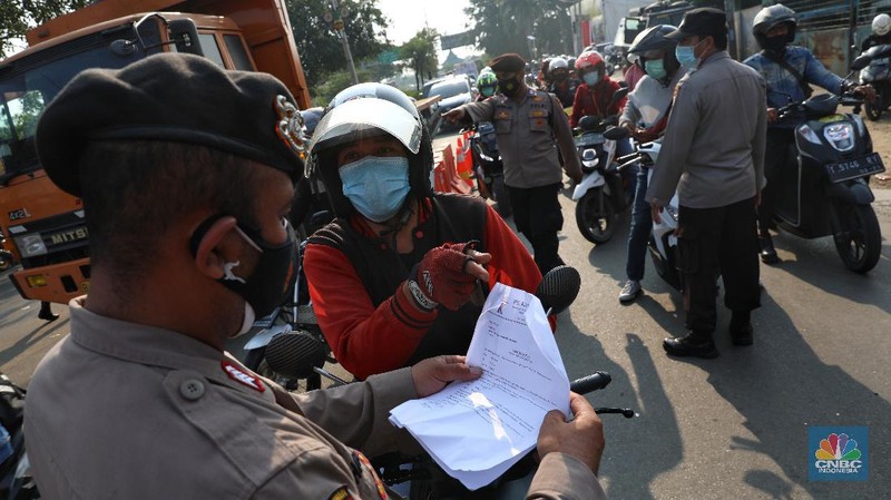 Petugas memeriksa dokumen pengendara motor di pos penyekatan, Jalur Pantura Kedungwaringin, perbatasan Kabupaten Bekasi-Karawang, Senin (10/5/2021).  Dari data yang didpat dari  jam 8.00 wib hingga 12.00 wib sebayak 415 kendaraan yang terdiri dari 342 kendaraan roda dua, 69 kendaraan roda empat, 2 travel dan 2 pickup telah di putar balik. (CNBC Indonesia/Andrean Kristianto)
