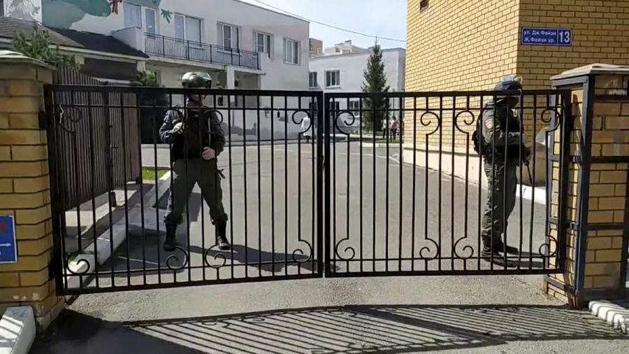 Firefighters walk past ambulances and police cars and a truck parked at a school after a shooting in Kazan, Russia, Tuesday, May 11, 2021. Russian media report that several people have been killed and wounded in a school shooting in the city of Kazan. Russia's state RIA Novosti news agency reported the shooting took place Tuesday morning, citing emergency services. (AP Photo/Roman Kruchinin)