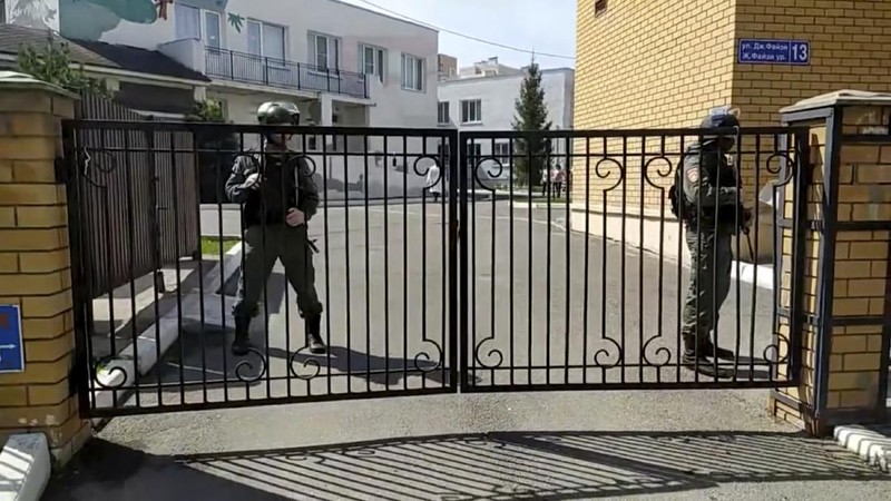 Firefighters walk past ambulances and police cars and a truck parked at a school after a shooting in Kazan, Russia, Tuesday, May 11, 2021. Russian media report that several people have been killed and wounded in a school shooting in the city of Kazan. Russia's state RIA Novosti news agency reported the shooting took place Tuesday morning, citing emergency services. (AP Photo/Roman Kruchinin)