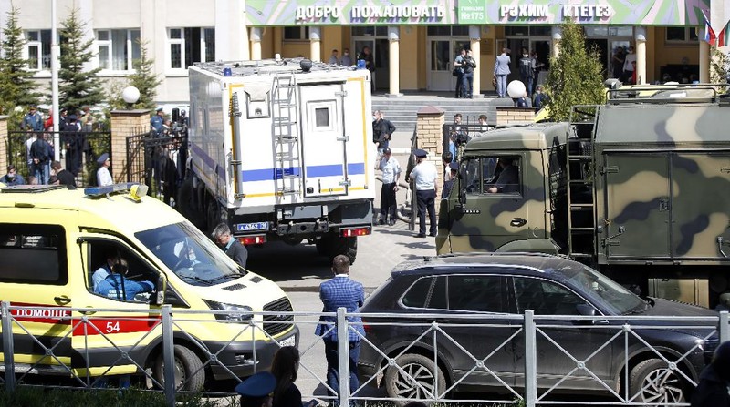 Firefighters walk past ambulances and police cars and a truck parked at a school after a shooting in Kazan, Russia, Tuesday, May 11, 2021. Russian media report that several people have been killed and wounded in a school shooting in the city of Kazan. Russia's state RIA Novosti news agency reported the shooting took place Tuesday morning, citing emergency services. (AP Photo/Roman Kruchinin)