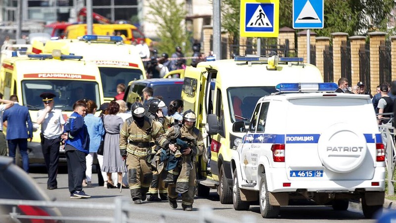 Firefighters walk past ambulances and police cars and a truck parked at a school after a shooting in Kazan, Russia, Tuesday, May 11, 2021. Russian media report that several people have been killed and wounded in a school shooting in the city of Kazan. Russia's state RIA Novosti news agency reported the shooting took place Tuesday morning, citing emergency services. (AP Photo/Roman Kruchinin)
