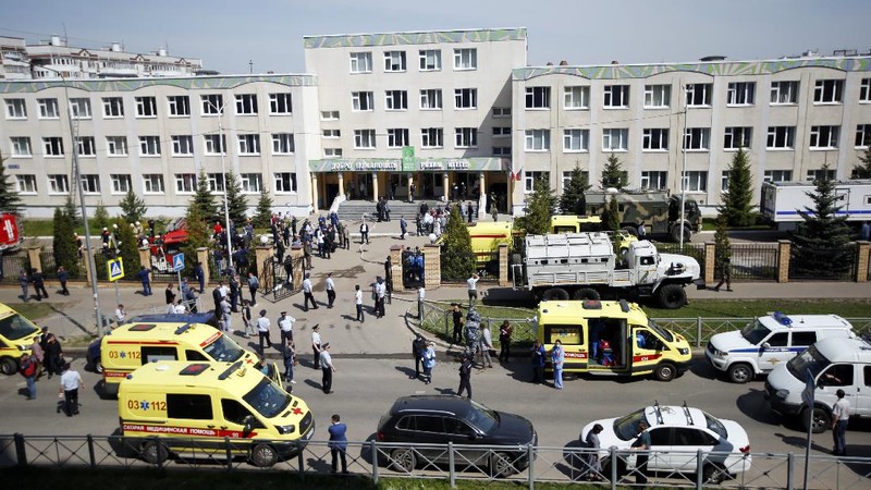 Firefighters walk past ambulances and police cars and a truck parked at a school after a shooting in Kazan, Russia, Tuesday, May 11, 2021. Russian media report that several people have been killed and wounded in a school shooting in the city of Kazan. Russia's state RIA Novosti news agency reported the shooting took place Tuesday morning, citing emergency services. (AP Photo/Roman Kruchinin)