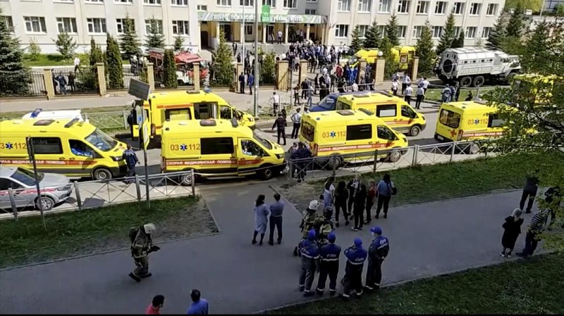 Firefighters walk past ambulances and police cars and a truck parked at a school after a shooting in Kazan, Russia, Tuesday, May 11, 2021. Russian media report that several people have been killed and wounded in a school shooting in the city of Kazan. Russia's state RIA Novosti news agency reported the shooting took place Tuesday morning, citing emergency services. (AP Photo/Roman Kruchinin)