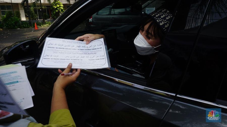 Warga menunaikan zakat fitrah dalam acara ulan suci Ramadan 1442 Hijriah di Gerai Zakat Infaq dan Shodaqoh drive thru di Masjid Nurul Hidayah, Jakarta, Selasa (11/5/2021). (CNBC Indonesia/Tri Susilo)