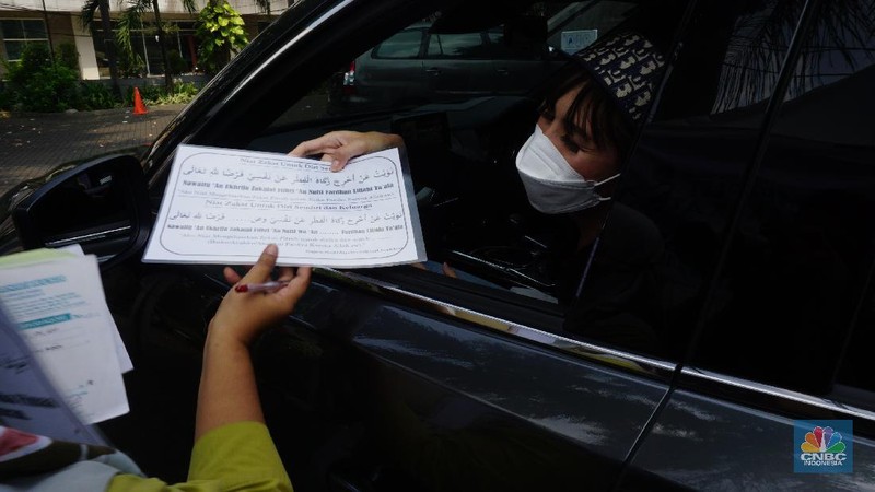 Warga menunaikan zakat fitrah dalam acara ulan suci Ramadan 1442 Hijriah di Gerai Zakat Infaq dan Shodaqoh drive thru di Masjid Nurul Hidayah, Jakarta, Selasa (11/5/2021). (CNBC Indonesia/Tri Susilo)