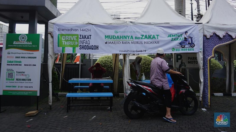 Warga menunaikan zakat fitrah dalam acara ulan suci Ramadan 1442 Hijriah di Gerai Zakat Infaq dan Shodaqoh drive thru di Masjid Nurul Hidayah, Jakarta, Selasa (11/5/2021). (CNBC Indonesia/Tri Susilo)