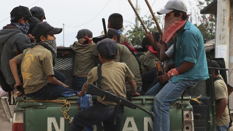 Children train with fake weapons during a display for the media designed to to attract the federal government's attention to the dangers of organized crime their town negotiates daily in Ayahualtempa, Guerrero state, Mexico, Wednesday, April 28, 2021. This long-abandoned and violent region is one of Mexico's poorest and also a key corridor for drug production and transit, especially heroin from opium poppies. (AP Photo/Marco Ugarte)