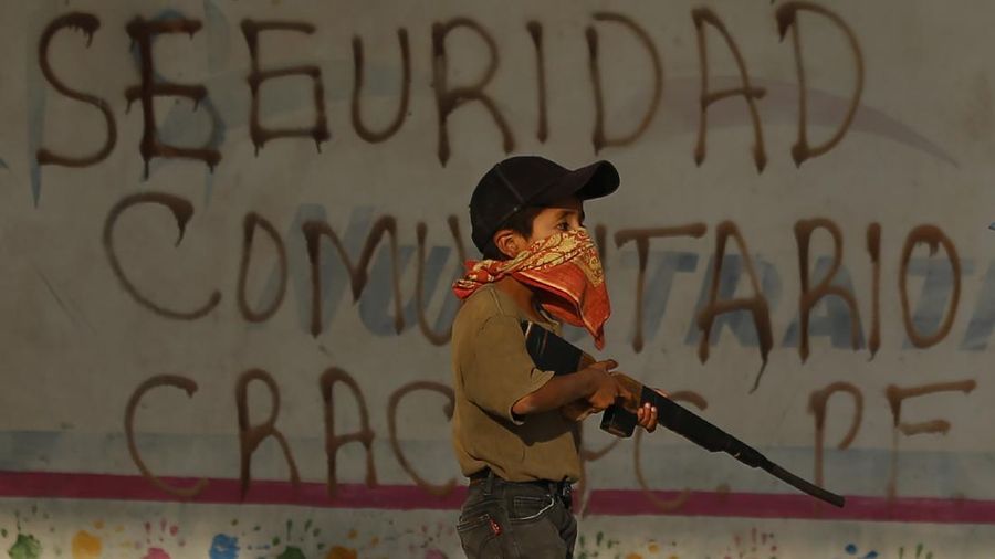 Children train with fake weapons during a display for the media designed to to attract the federal government's attention to the dangers of organized crime their town negotiates daily in Ayahualtempa, Guerrero state, Mexico, Wednesday, April 28, 2021. This long-abandoned and violent region is one of Mexico's poorest and also a key corridor for drug production and transit, especially heroin from opium poppies. (AP Photo/Marco Ugarte)
