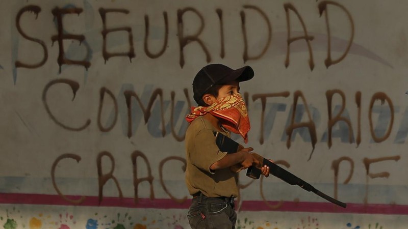 Children train with fake weapons during a display for the media designed to to attract the federal government's attention to the dangers of organized crime their town negotiates daily in Ayahualtempa, Guerrero state, Mexico, Wednesday, April 28, 2021. This long-abandoned and violent region is one of Mexico's poorest and also a key corridor for drug production and transit, especially heroin from opium poppies. (AP Photo/Marco Ugarte)
