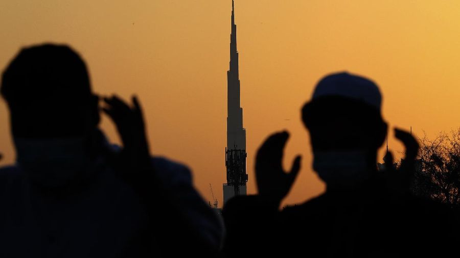 With the world's tallest building, Burj Khalifa, in background, Muslim men wearing masks to curb the spread of coronavirus outbreak perform an Eid al-Fitr prayer marking the end of the holy fasting month of Ramadan in Dubai, United Arab Emirates, Thursday, May 13, 2021. (AP Photo/Kamran Jebreili)