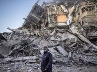 A Palestinian man looks at the destruction of a building hit by Israeli airstrikes in Gaza City, Thursday, May 13, 2021. Gaza braced for more Israeli airstrikes and communal violence raged across Israel after weeks of protests and violence in Jerusal