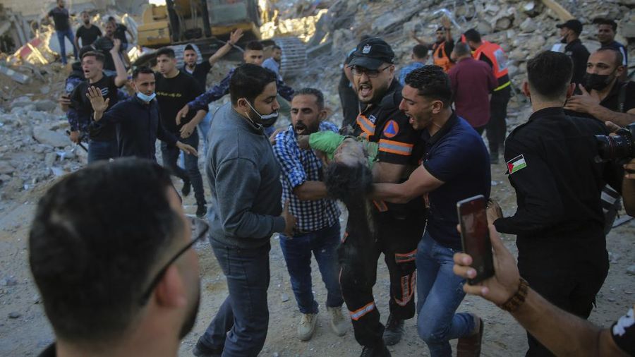 Palestinians carry the body of a child found in the rubble of a house belonging to the Al-Tanani family, that was destroyed in Israeli airstrikes in town of Beit Lahiya, northern Gaza Strip, Thursday, May 13, 2021. (AP Photo/Abdel Kareem Hana)