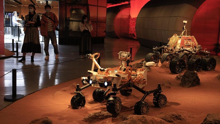 Visitors pass by an exhibition depicting rovers on Mars in Beijing on Friday, May 14, 2021. China says its Mars probe and accompanying rover are to land on the red planet sometime between early Saturday morning and Wednesday Beijing time. (AP Photo/Ng Han Guan)