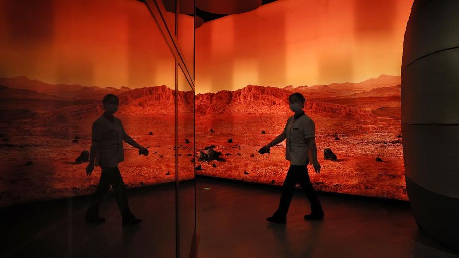 A woman walks past an exhibition depicting Mars landscape in Beijing on Friday, May 14, 2021. China says its Mars probe and accompanying rover are to land on the red planet sometime between early Saturday morning and Wednesday Beijing time. (AP Photo/Ng Han Guan)