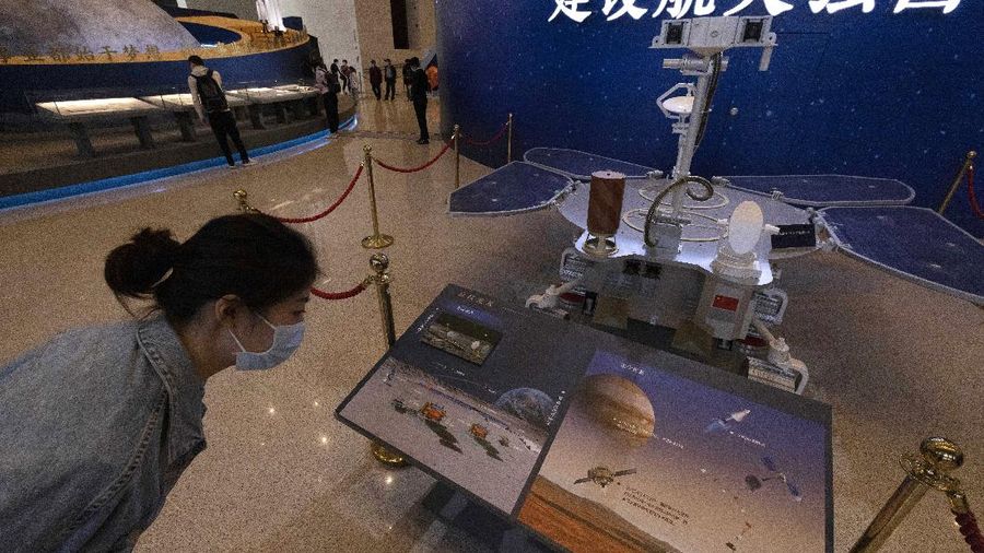 A visitor to an exhibition on China's space program looks at a life size model of the Chinese Mars rover Zhurong, named after the Chinese god of fire, at the National Museum in Beijing on Thursday, May 6, 2021. China has landed a spacecraft on Mars for the first time in the latest advance for its space program. The official Xinhua News Agency said Saturday, May 15, that the lander had touched down, citing the China National Space Administration. Chinese characters read: Build a Space Power. (AP Photo/Ng Han Guan)