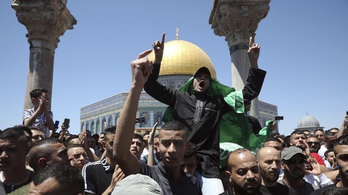 A Muslim worshipper wears a Hamas flag during a protest against Israeli airstrikes on the Gaza Strip following Friday prayers at the Dome of the Rock Mosque in the Al-Aqsa Mosque compound in the Old City of Jerusalem, Friday, May 14, 2021. (AP Photo/Mahmoud Illean)