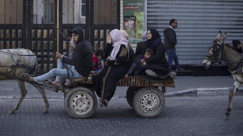 Palestinians flee their homes to a U.N. school after overnight Israeli heavy missile strikes on their neighborhoods in the outskirts of Gaza City, Friday, May 14, 2021. (AP Photo/Khalil Hamra)