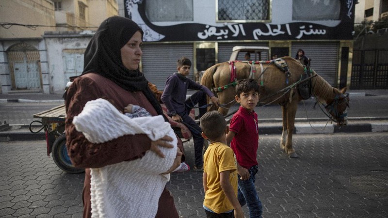 Palestinians flee their homes to a U.N. school after overnight Israeli heavy missile strikes on their neighborhoods in the outskirts of Gaza City, Friday, May 14, 2021. (AP Photo/Khalil Hamra)