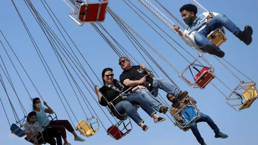 People enjoy their time in a wave swinger Friday, May 14, 2021 at Chicago's Navy Pier. The U.S. Centers for Disease Control and Prevention eased its guidelines, saying fully vaccinated people can resume activities without wearing masks. (AP Photo/Shafkat Anowar)