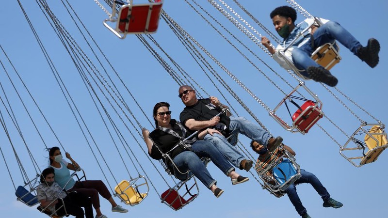 People enjoy their time in a wave swinger Friday, May 14, 2021 at Chicago's Navy Pier. The U.S. Centers for Disease Control and Prevention eased its guidelines, saying fully vaccinated people can resume activities without wearing masks. (AP Photo/Shafkat Anowar)
