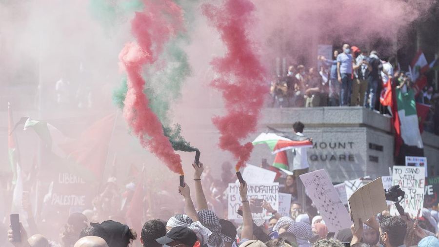 Demonstrators holding flags stand on the top of a building during a protest outside Israeli Consulate against Israel and in support of Palestinians, Saturday, May 15, 2021 in the Westwood section of Los Angeles. (AP Photo/Ringo H.W. Chiu)