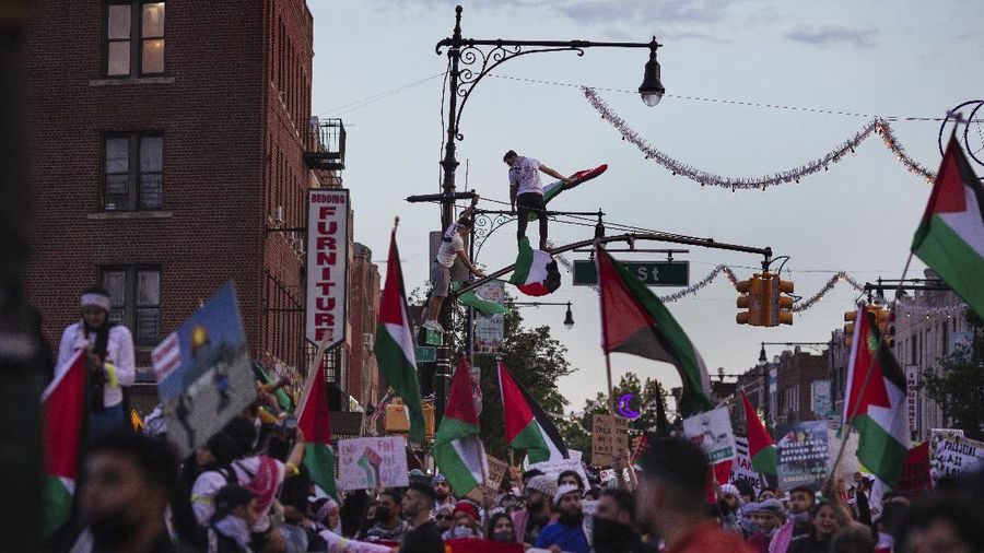 Demonstrators holding flags stand on the top of a building during a protest outside Israeli Consulate against Israel and in support of Palestinians, Saturday, May 15, 2021 in the Westwood section of Los Angeles. (AP Photo/Ringo H.W. Chiu)