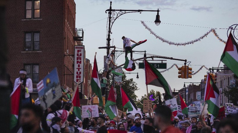 Demonstrators holding flags stand on the top of a building during a protest outside Israeli Consulate against Israel and in support of Palestinians, Saturday, May 15, 2021 in the Westwood section of Los Angeles. (AP Photo/Ringo H.W. Chiu)