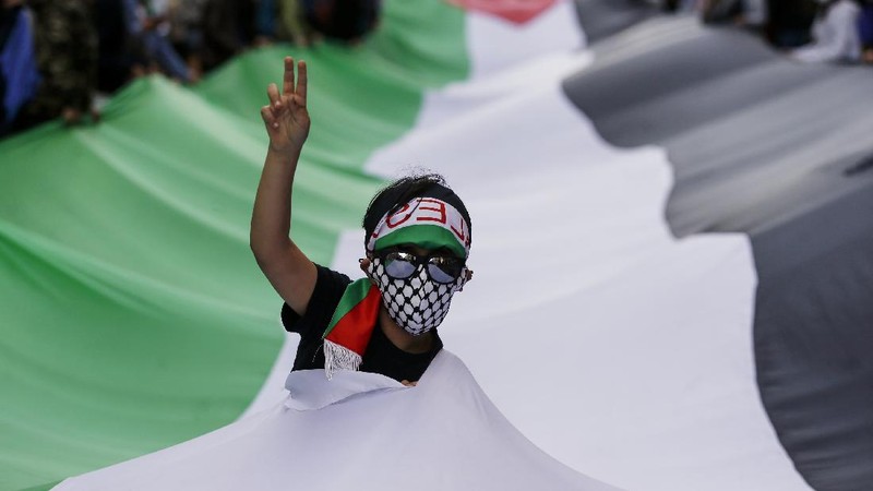 Demonstrators holding flags stand on the top of a building during a protest outside Israeli Consulate against Israel and in support of Palestinians, Saturday, May 15, 2021 in the Westwood section of Los Angeles. (AP Photo/Ringo H.W. Chiu)