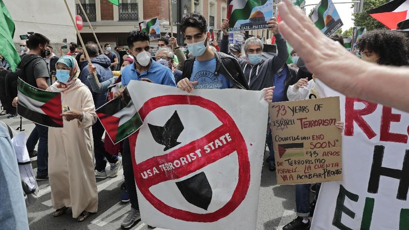 Demonstrators holding flags stand on the top of a building during a protest outside Israeli Consulate against Israel and in support of Palestinians, Saturday, May 15, 2021 in the Westwood section of Los Angeles. (AP Photo/Ringo H.W. Chiu)