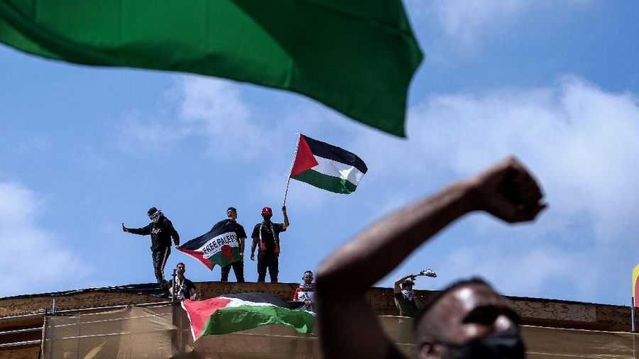 Demonstrators holding flags stand on the top of a building during a protest outside Israeli Consulate against Israel and in support of Palestinians, Saturday, May 15, 2021 in the Westwood section of Los Angeles. (AP Photo/Ringo H.W. Chiu)