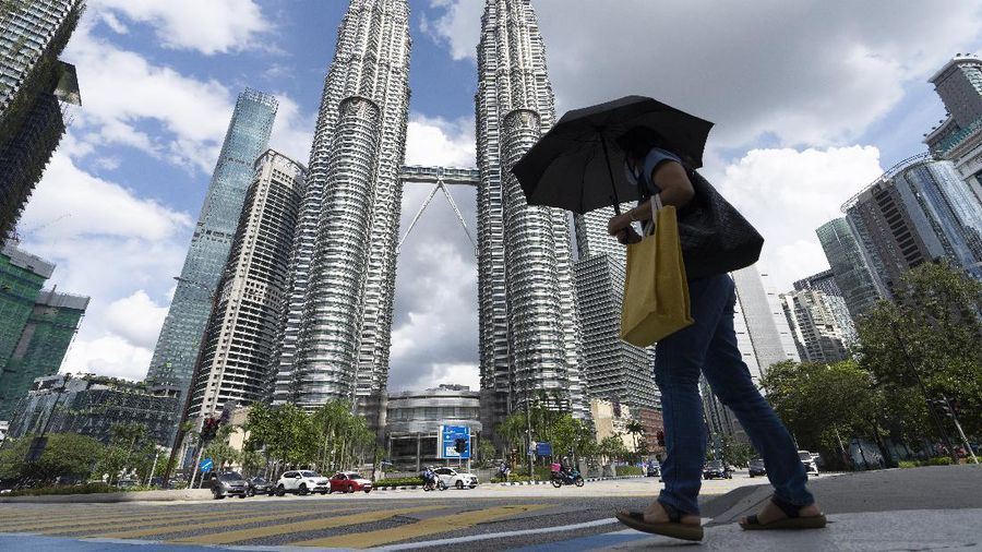 A woman wearing a face mask walks in front of the Twin Towers during the first day of third Movement Control Order (MCO) in Kuala Lumpur, Malaysia, Friday, May 7, 2021. Kuala Lumpur and few other cities will be placed under the Movement Control Order (MCO) as the number of COVID-19 cases and clusters continue to rise. (AP Photo/Vincent Thian)