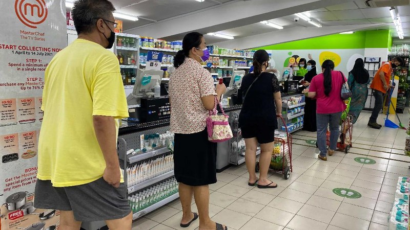 People wear masks and observe social distancing while lining up to pay at a supermarket in Singapore, Friday, May 14, 2021. Singapore further tightened its COVID-19 measures as it sought to control an increase in untraceable coronavirus infections in the city-state. (AP Photo/Zen Soo