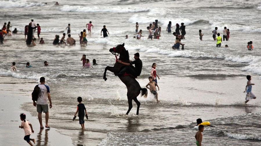 A Palestinians man plays with his child as the family enjoys a day at the beach of the Mediterranean sea in Gaza City, Friday, Sept. 18, 2020. (AP Photo/Hatem Moussa)