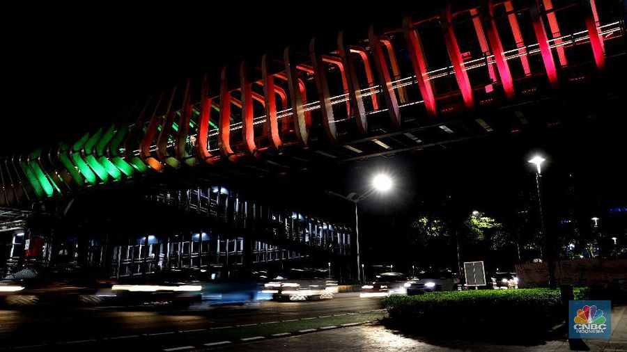 Warga melintas di JPO Gelora Bung Karno yang berhias warna warni bendera Palestina, Jakarta, Rabu, 19/5. Pemerintah Provinsi DKI Jakarta ikut meramaikan dukungan untuk . Aksi solidaritas dilakukan dengan menampilkan warna-warna khas bendera Negara Palestina di 10 Jembatan Penyeberangan Orang (JPO) di Ibu Kota. Tujuan menampilkan warna bendera Palestina di JPO itu yakni untuk menyampaikan rasa kepedulian terhadap para warga Palestina yang menjadi korban kekejaman Zionis Israel. 10 lokasi JPO dan terowongan di Jakarta yang dihiasi lampu berwarna bendera Palestina, antara lain JPO Polda Metro Jaya, JPO GBK, JPO Bunsen, JPO Sumarni, JPO Jelambar, JPO Daan Mogot, JPO Pasar Minggu, JPO Senen, Terowongan Kendal, dan Simpang Susun Semanggi. Beberapa pengunjung yang lewat JPO juga asik mengabadikan momen lampu yang berhiaskan bendera Palestina. (CNBC Indonesia/ Muhammad Sabki)