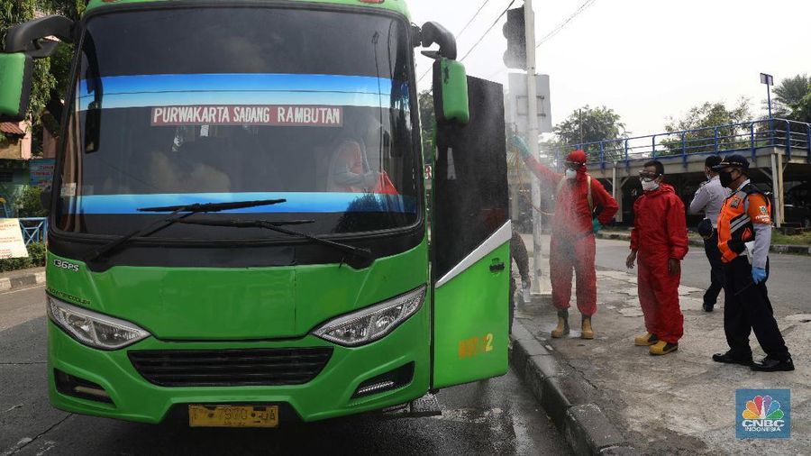 Petugas damkar menyemprot disinfektan kepada bus yang tiba dari daerah di terminal Kp Rambutan, Rabu, 19/5. Pasca berakhirnya peraturan larangan mudik Lebaran 2021, Terminal Kampung Rambutan kembali beroperasi melayani perjalanan ke luar kota dan ramai oleh penumpang tujuan Sumatra yang tidak kembali ke kampung halamannya pada Hari Raya Idul Fitri 1442 Hijriah lalu. Pantauan CNBC Indonesia pemudik dari luar Jabodetabek yang mulai berdatangan di terminal yang berlokasi di Kecamatan Ciracas, Jakarta Timur itu langsung disemprot disinfektan. Petugas juga melakukan tes rapid antigen secara acak bagi penumpang yang datang dari luar Jabodetabek. Pemandangan lain dilokasi keberangkatan juga ramai warga yang hendak pergi keluar kota. Terminal Kampung Rambutan menjadi salah satu terminal di Jakarta yang ditutup sementara selama periode larangan mudik Lebaran, 6-17 Mei 2021. Layanan bus antar kota antar provinsi (AKAP) tidak beroperasi selama periode tersebut. (CNBC Indonesia/ Muhammad Sabki)
