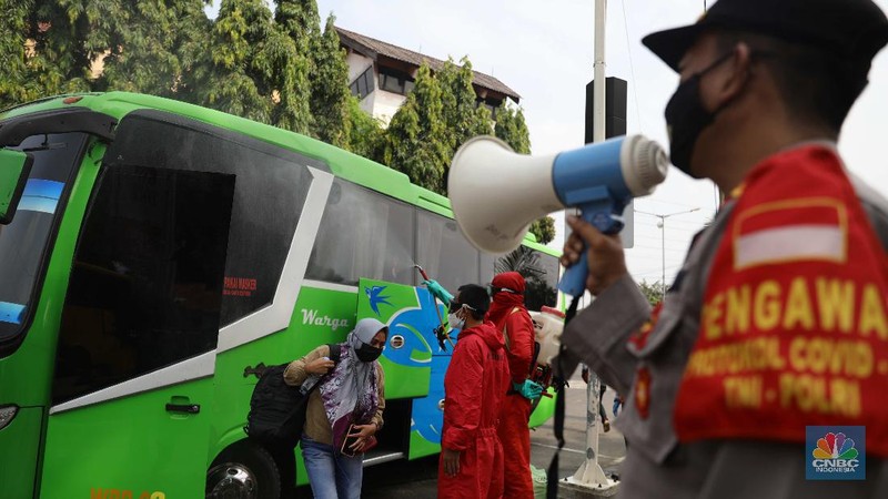 Petugas damkar menyemprot disinfektan kepada bus yang tiba dari daerah di terminal Kp Rambutan, Rabu, 19/5. Pasca berakhirnya peraturan larangan mudik Lebaran 2021, Terminal Kampung Rambutan kembali beroperasi melayani perjalanan ke luar kota dan ramai oleh penumpang tujuan Sumatra yang tidak kembali ke kampung halamannya pada Hari Raya Idul Fitri 1442 Hijriah lalu. Pantauan CNBC Indonesia pemudik dari luar Jabodetabek yang mulai berdatangan di terminal yang berlokasi di Kecamatan Ciracas, Jakarta Timur itu langsung disemprot disinfektan. Petugas juga melakukan tes rapid antigen secara acak bagi penumpang yang datang dari luar Jabodetabek. Pemandangan lain dilokasi keberangkatan juga ramai warga yang hendak pergi keluar kota. Terminal Kampung Rambutan menjadi salah satu terminal di Jakarta yang ditutup sementara selama periode larangan mudik Lebaran, 6-17 Mei 2021. Layanan bus antar kota antar provinsi (AKAP) tidak beroperasi selama periode tersebut.  (CNBC Indonesia/ Muhammad Sabki)