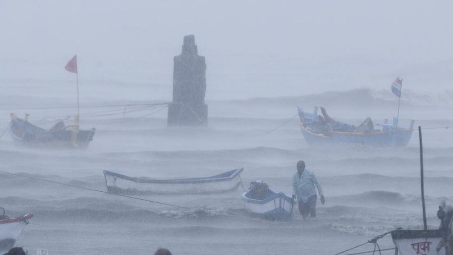 A motorist and a woman wade through a waterlogged street after heavy rains in Ahmedabad, India, Tuesday, May 18, 2021. Cyclone Tauktae, the most powerful storm to hit the region in more than two decades, packed sustained winds of up to 210 kilometers (130 miles) per hour when it came ashore in Gujarat state late Monday. (AP Photo/Ajit Solanki)