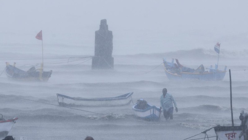 A motorist and a woman wade through a waterlogged street after heavy rains in Ahmedabad, India, Tuesday, May 18, 2021. Cyclone Tauktae, the most powerful storm to hit the region in more than two decades, packed sustained winds of up to 210 kilometers (130 miles) per hour when it came ashore in Gujarat state late Monday. (AP Photo/Ajit Solanki)