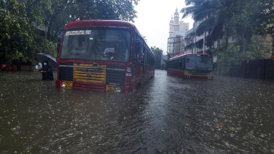 A motorist and a woman wade through a waterlogged street after heavy rains in Ahmedabad, India, Tuesday, May 18, 2021. Cyclone Tauktae, the most powerful storm to hit the region in more than two decades, packed sustained winds of up to 210 kilometers (130 miles) per hour when it came ashore in Gujarat state late Monday. (AP Photo/Ajit Solanki)